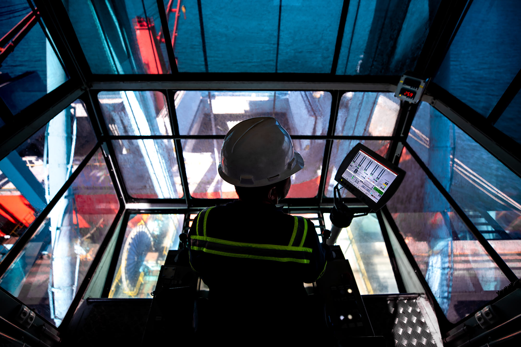 A view from the control booth of an industrial marine crane with technician silhouette |  Scott Gable industrial photographer 