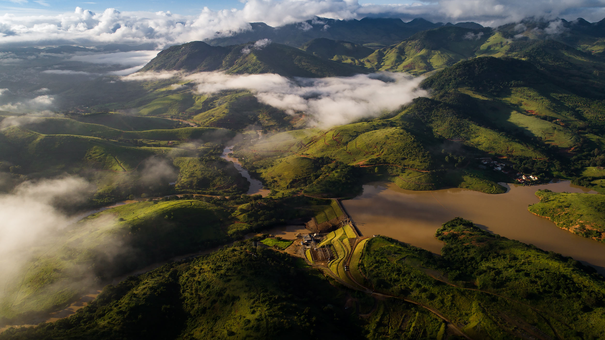 Aerial view of hydroelectric dam in Brazil with green hills and clouds | Scott Gable industrial photographer