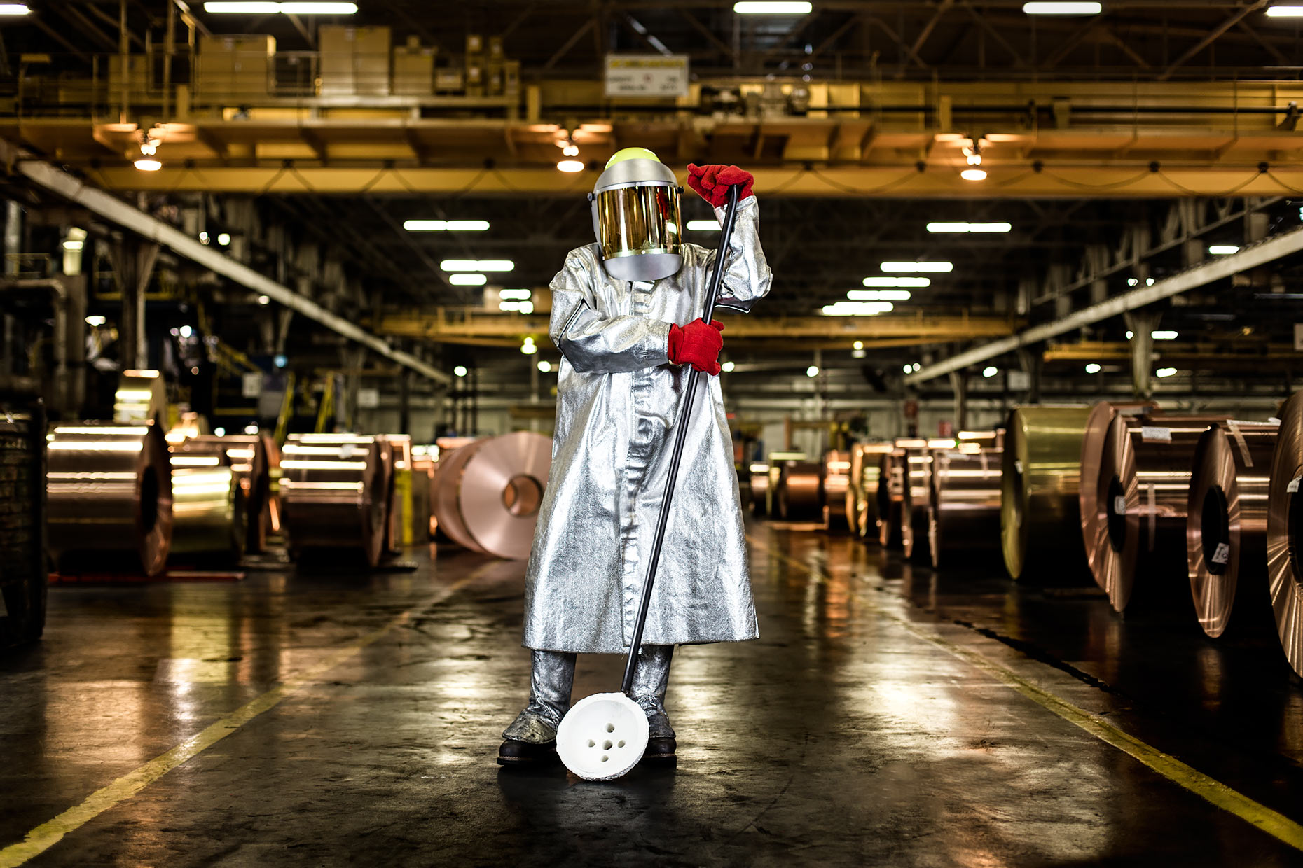 A brass manufacturing technician in full safety gear standing among brass rolls  | Scott Gable industrial photographer