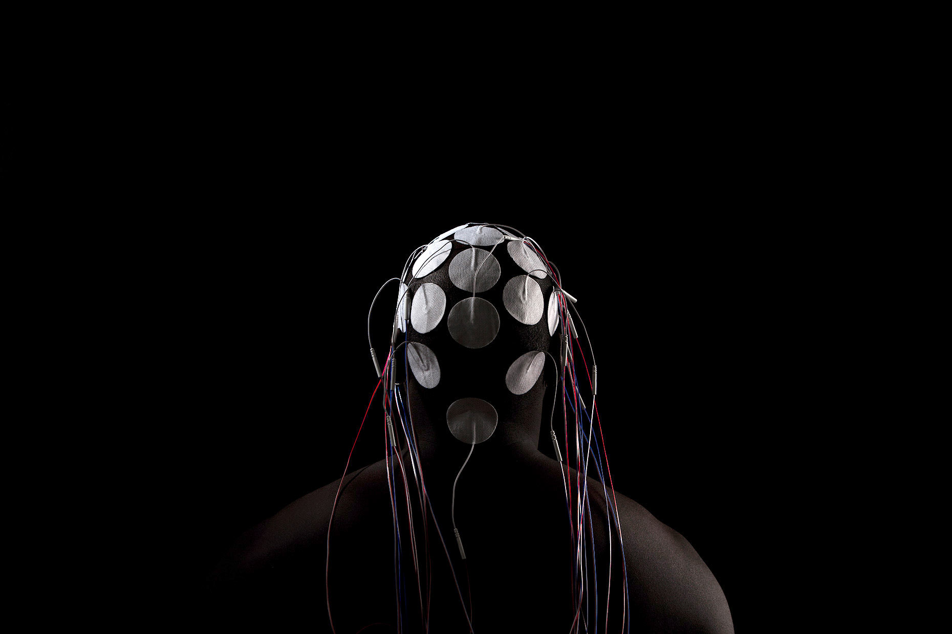 Electrodes on the back of the head of a bald, African American, male model with dark background | Scott Gable industrial photographer